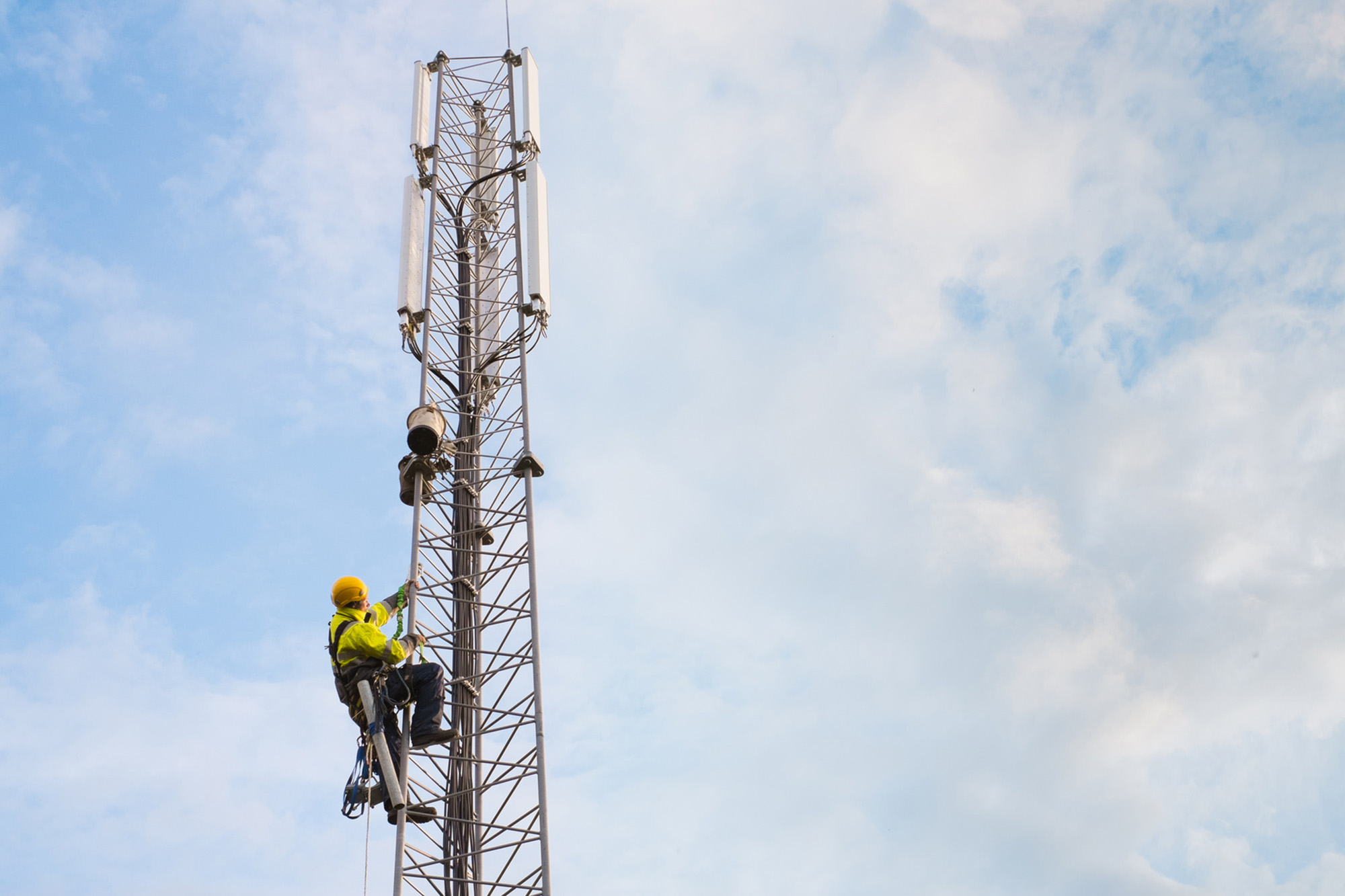 Working at heights, technician climbs up on a communications tower